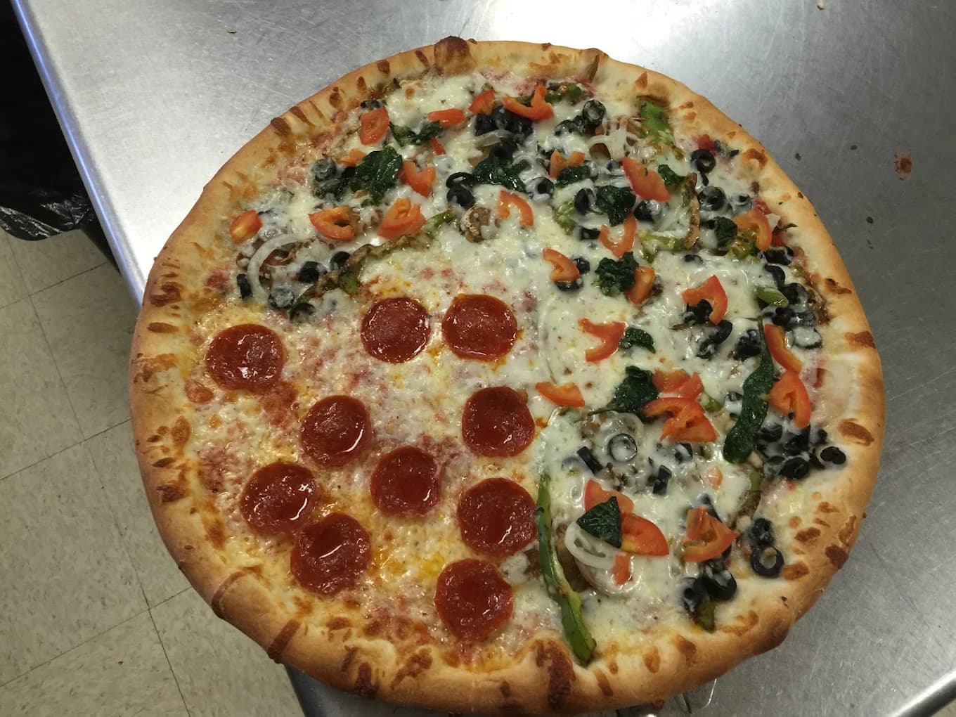 A pizza with sections of pepperoni and vegetable toppings